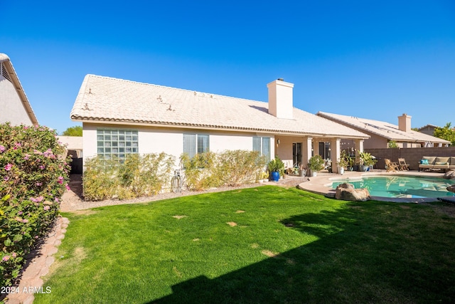 back of house featuring a lawn, a patio area, and a fenced in pool