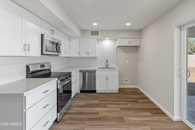 kitchen featuring visible vents, baseboards, appliances with stainless steel finishes, white cabinetry, and a sink