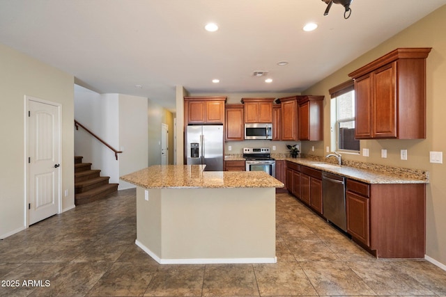 12217 W Planada Ln, Sun City, AZ 85373 - kitchen with light stone counters, brown cabinets, a sink, appliances with stainless steel finishes, and a center island