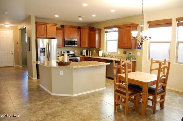 12217 W Planada Ln, Sun City, AZ 85373 - kitchen featuring recessed lighting, appliances with stainless steel finishes, brown cabinets, a center island, and a notable chandelier