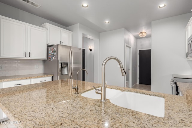 kitchen featuring appliances with stainless steel finishes, white cabinetry, a sink, tasteful backsplash, and recessed lighting