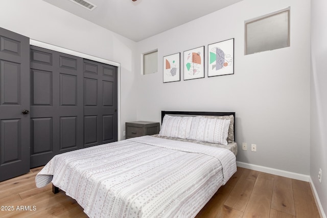 bedroom featuring a closet, light wood-style floors, and baseboards