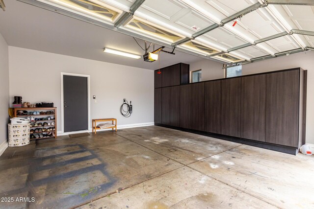 garage featuring a garage door opener and baseboards