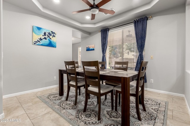 dining space with a tray ceiling, a ceiling fan, recessed lighting, light tile patterned flooring, and baseboards