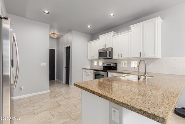 kitchen featuring appliances with stainless steel finishes, a sink, light stone countertops, tasteful backsplash, and recessed lighting