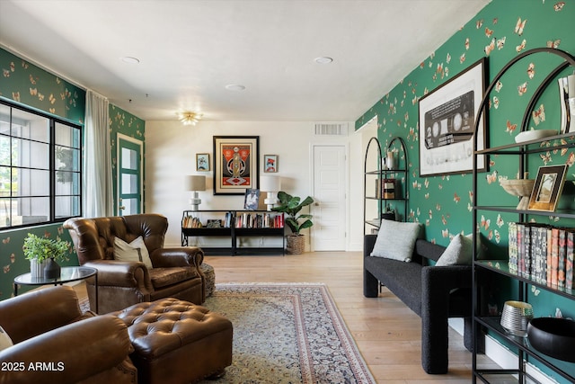 living area featuring wood finished floors, visible vents, and wallpapered walls