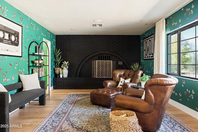 living area with an accent wall, wood finished floors, and visible vents