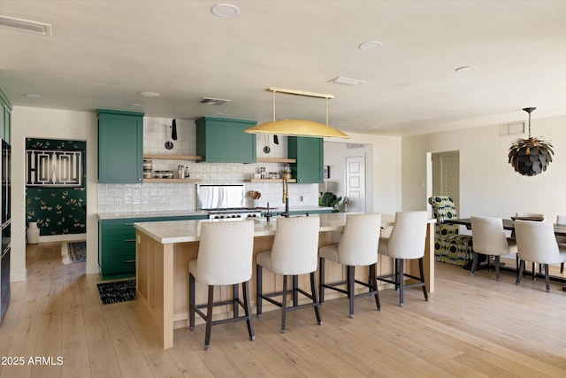 kitchen featuring green cabinets, open shelves, light wood finished floors, and light countertops