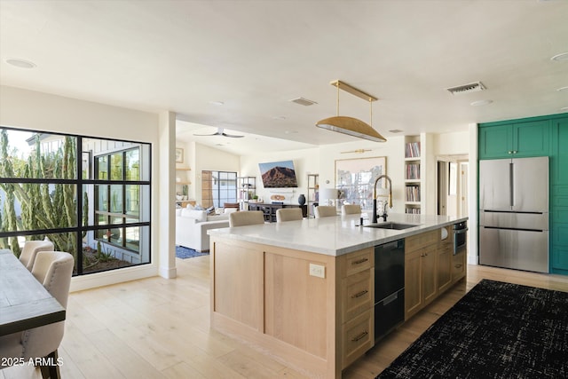 kitchen featuring stainless steel appliances, visible vents, light wood-style flooring, open floor plan, and a sink