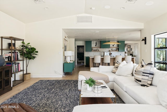 living room featuring baseboards, visible vents, vaulted ceiling, and light wood finished floors