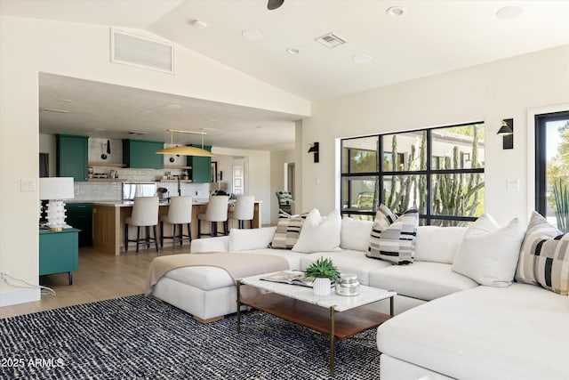 living room with lofted ceiling, visible vents, and light wood finished floors