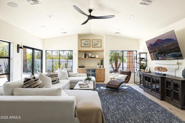 living room featuring light wood-type flooring, wine cooler, visible vents, and vaulted ceiling