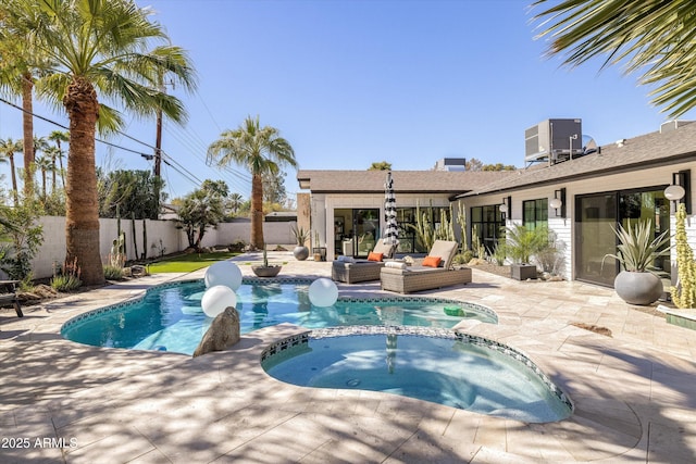 view of swimming pool featuring a pool with connected hot tub, a fenced backyard, central AC, and a patio