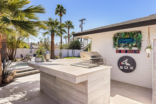 view of patio featuring an outdoor kitchen, a grill, and fence