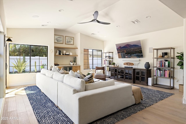 living area featuring ceiling fan, visible vents, vaulted ceiling, and wood finished floors