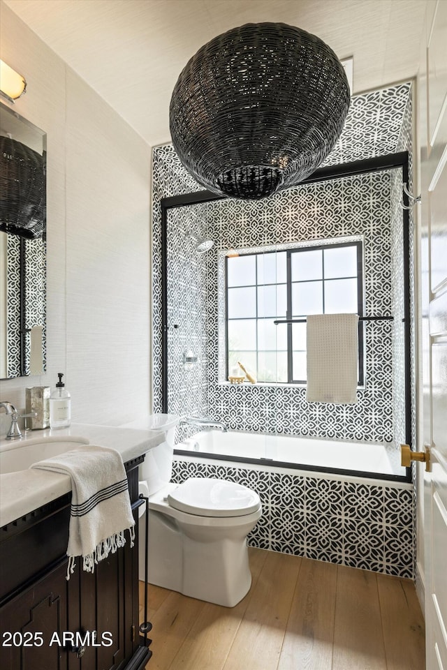 bathroom with toilet, tiled shower / bath combo, hardwood / wood-style floors, and vanity