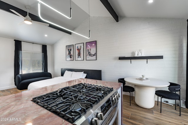 kitchen with lofted ceiling, hardwood / wood-style floors, high end stainless steel range oven, and brick wall