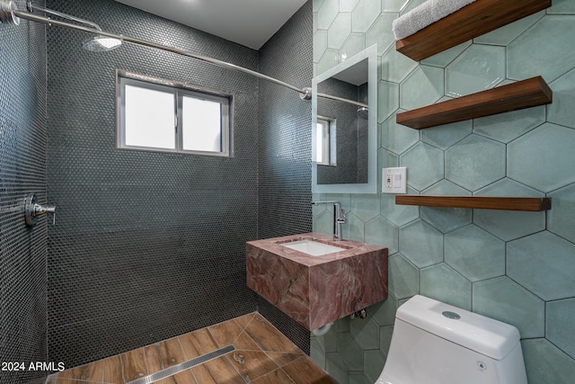 bathroom with toilet, a shower, tile walls, wood-type flooring, and vanity