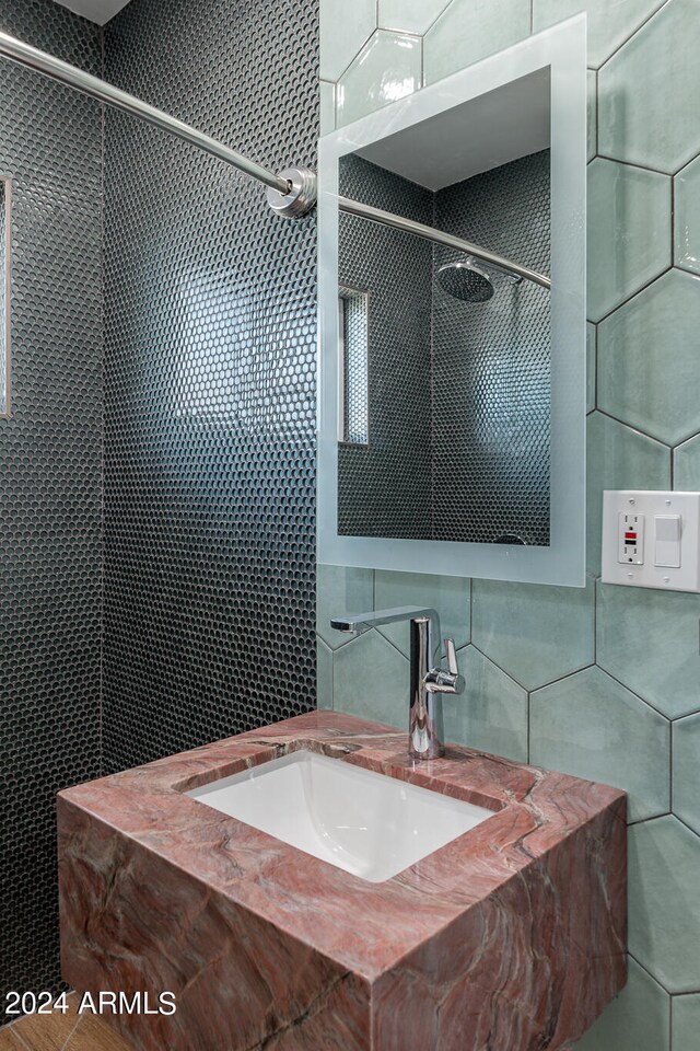 bathroom with tile walls, sink, and tiled shower