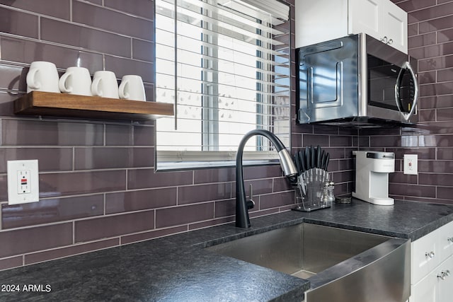 kitchen featuring backsplash, white cabinetry, and sink