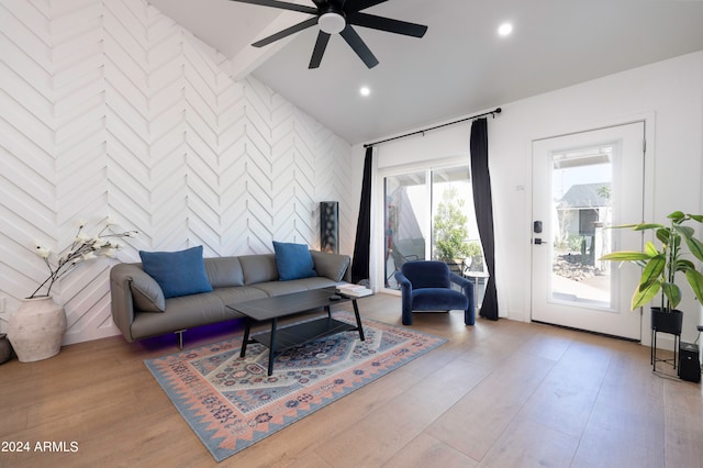 living room with light hardwood / wood-style flooring, ceiling fan, and vaulted ceiling with beams