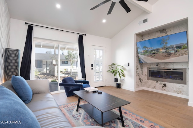 living room featuring vaulted ceiling, a premium fireplace, light hardwood / wood-style flooring, and ceiling fan