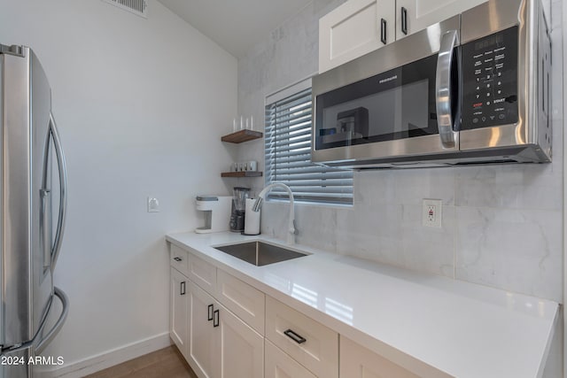 kitchen featuring stainless steel appliances, sink, and white cabinetry