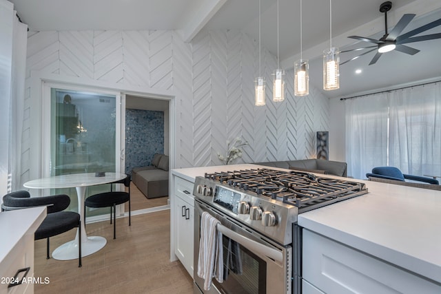 kitchen with light wood-type flooring, decorative light fixtures, white cabinetry, stainless steel range, and ceiling fan