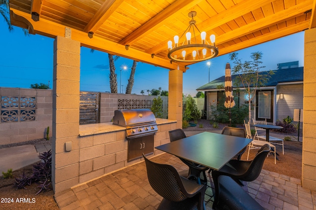 patio terrace at dusk featuring an outdoor kitchen and area for grilling