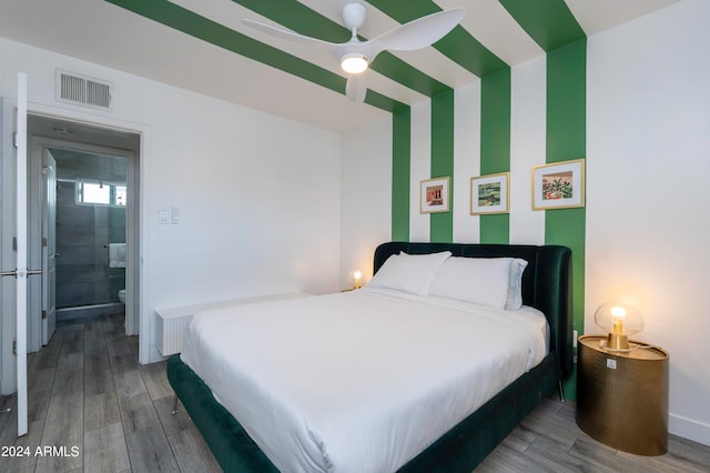 bedroom featuring ceiling fan, ensuite bathroom, and hardwood / wood-style flooring