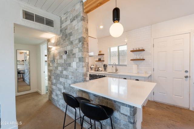 kitchen with decorative light fixtures, white cabinetry, sink, kitchen peninsula, and a breakfast bar