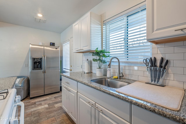 kitchen with light hardwood / wood-style flooring, stainless steel fridge with ice dispenser, sink, white range oven, and white cabinets