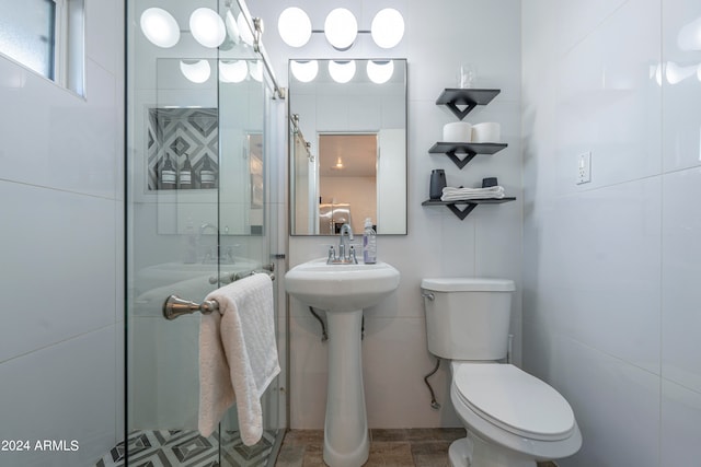 bathroom featuring toilet, tile patterned floors, and a shower with door