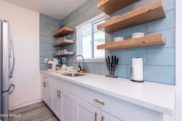 kitchen featuring stainless steel fridge, sink, light stone countertops, dark hardwood / wood-style floors, and white cabinets