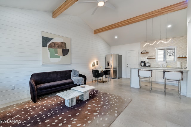 living room featuring beamed ceiling, high vaulted ceiling, wood walls, and ceiling fan