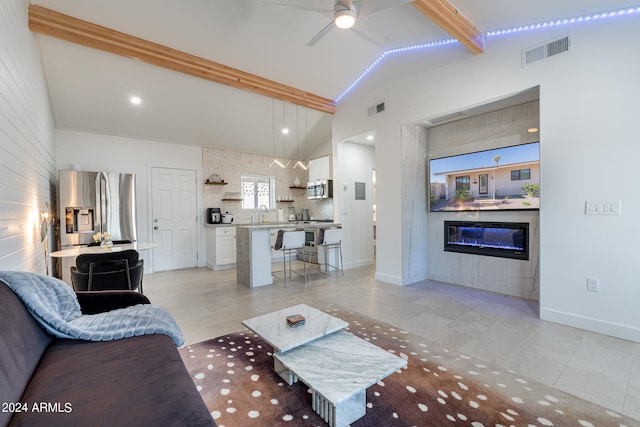 tiled living room with sink, ceiling fan, and vaulted ceiling with beams