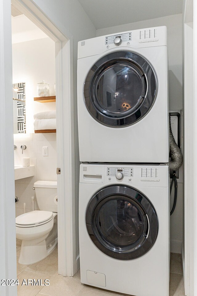 washroom featuring stacked washer and clothes dryer and light tile patterned flooring