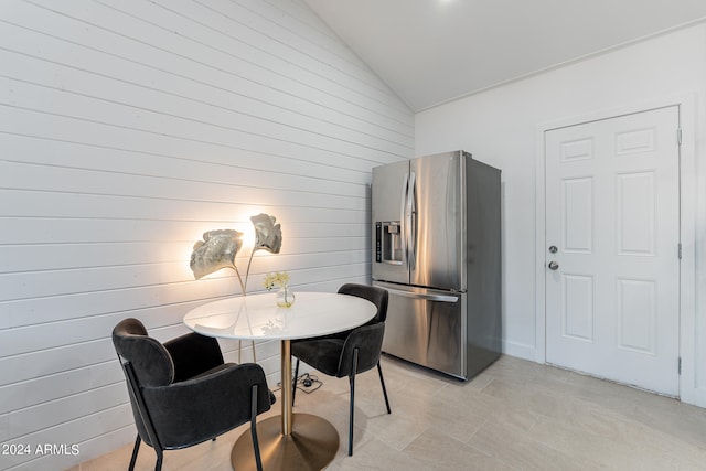 dining room with lofted ceiling and wooden walls