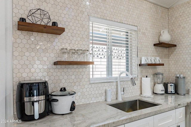 kitchen featuring ornamental molding, light stone counters, sink, and white cabinets