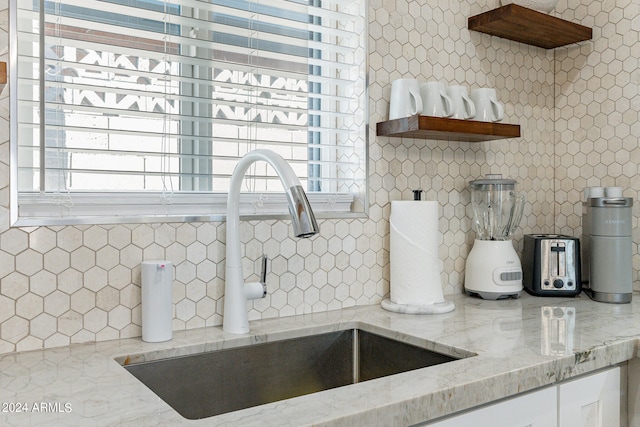 details with light stone counters, sink, and white cabinetry