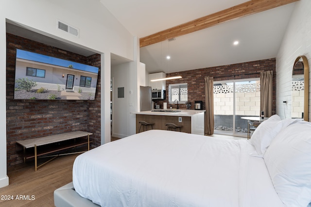 bedroom with stainless steel fridge, wood-type flooring, access to exterior, vaulted ceiling with beams, and brick wall