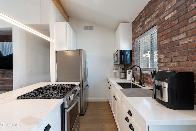 kitchen featuring light wood-type flooring, white cabinetry, stainless steel appliances, sink, and light stone countertops