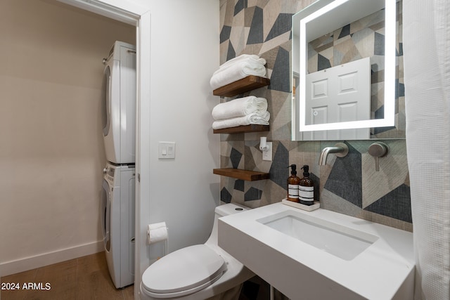 bathroom with wood-type flooring, toilet, and stacked washer / drying machine