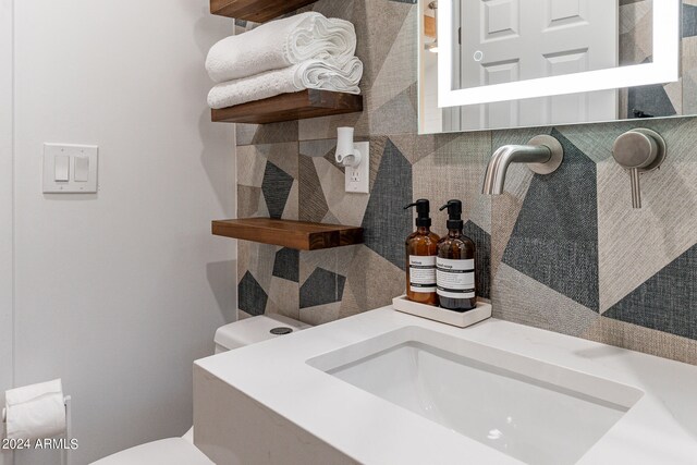 bathroom featuring vanity, toilet, and decorative backsplash