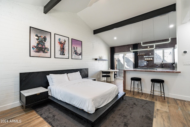 bedroom featuring hardwood / wood-style flooring, brick wall, sink, and vaulted ceiling with beams