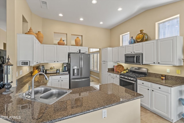 kitchen featuring stainless steel appliances, dark stone countertops, white cabinetry, and sink