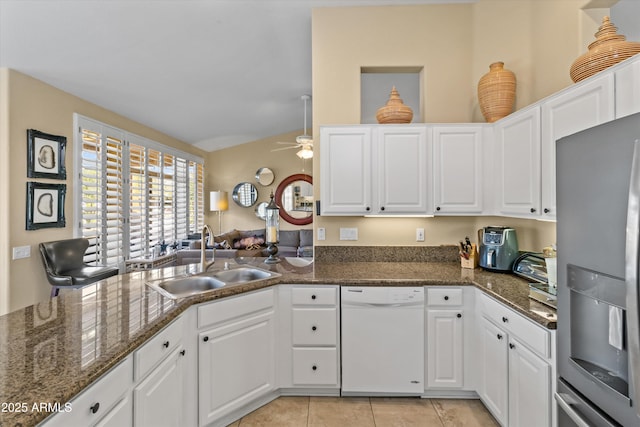 kitchen featuring stainless steel fridge, white dishwasher, dark stone counters, white cabinets, and sink