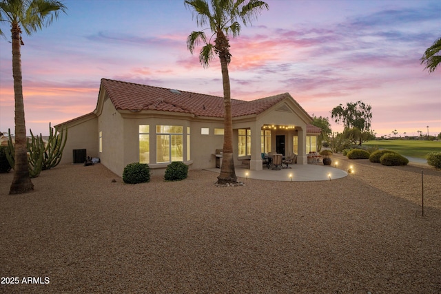 back house at dusk featuring a patio area