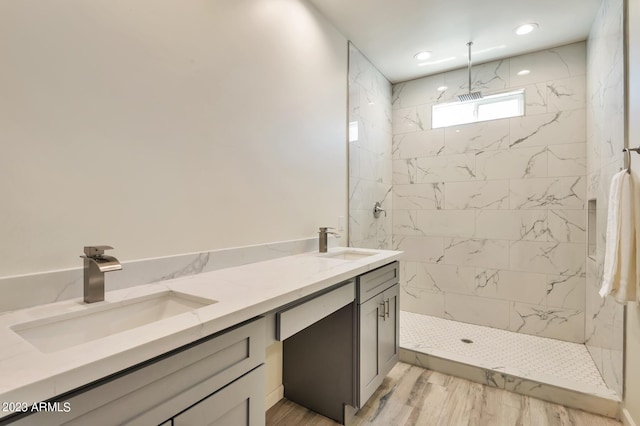 bathroom with a tile shower and vanity