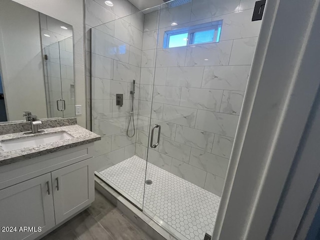 bathroom with hardwood / wood-style floors, walk in shower, and vanity